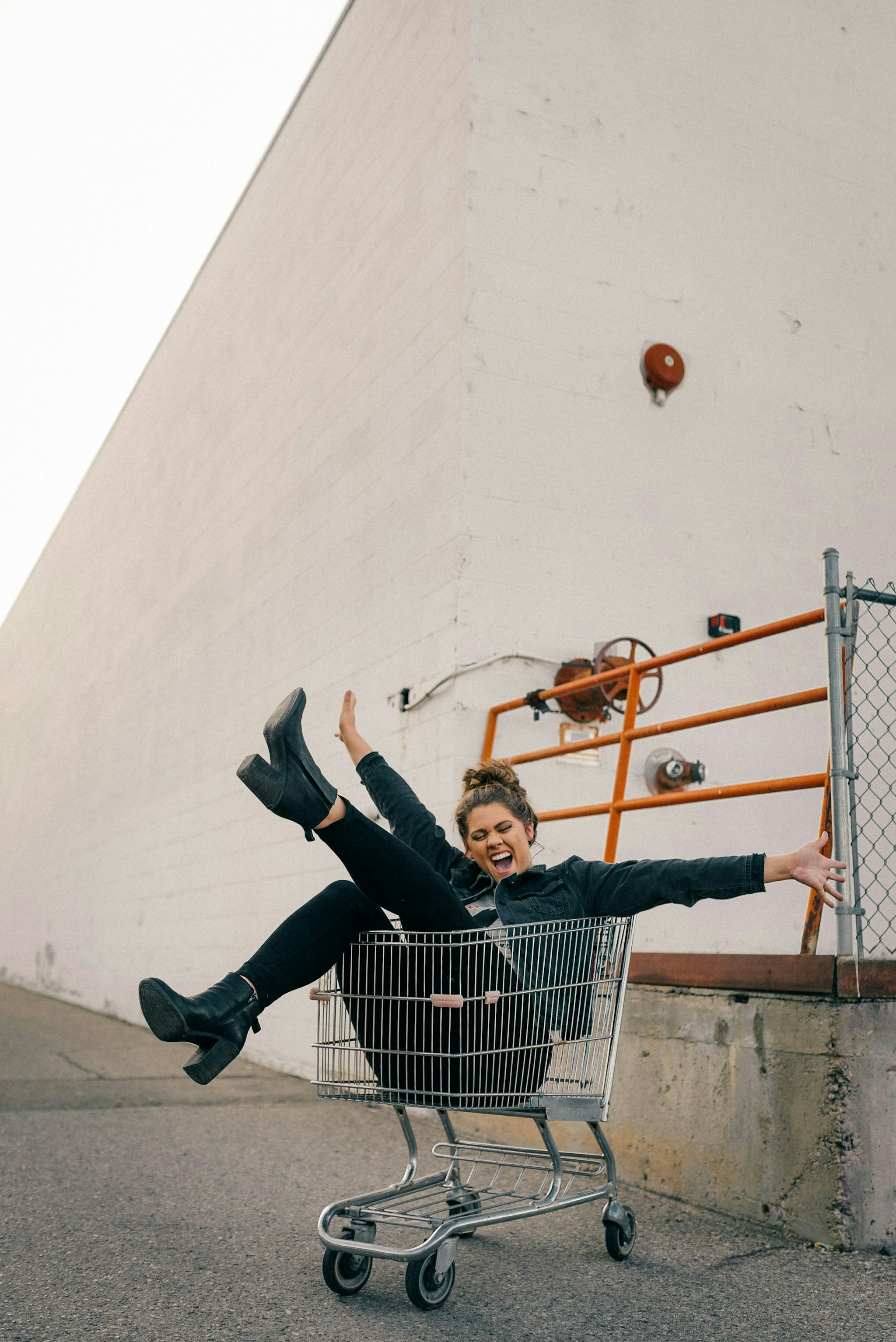 An image of a happy woman smiling and sitting in a shopping trolley